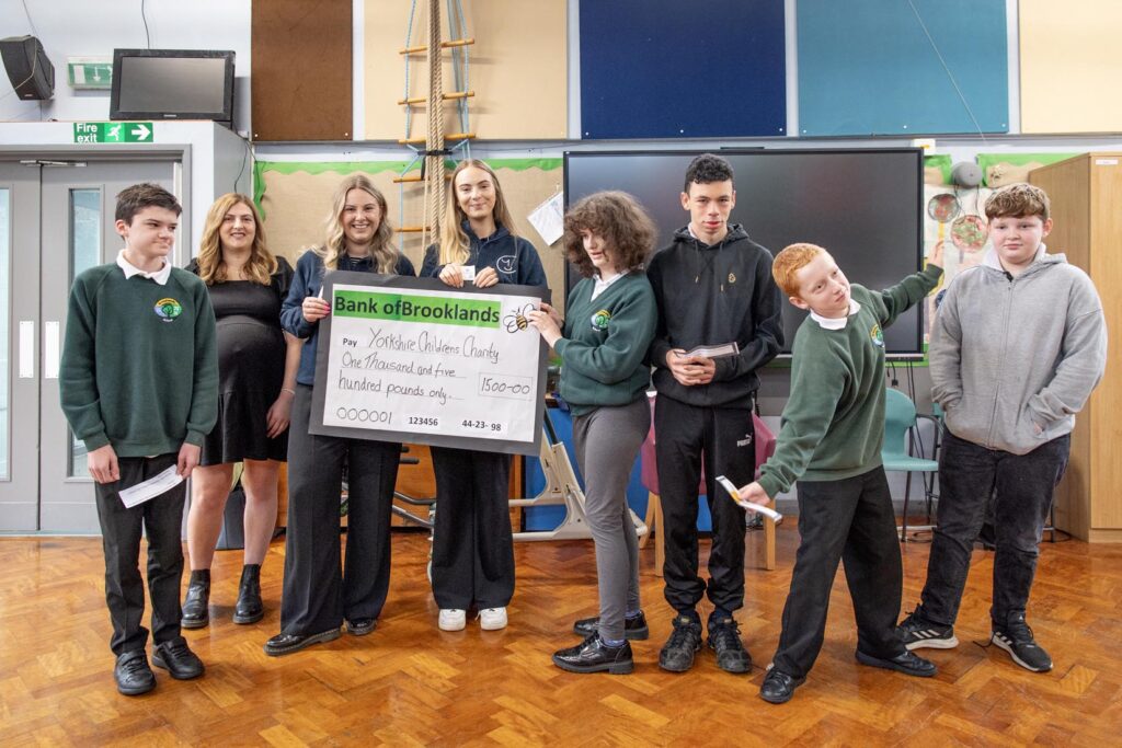 Staff from Yorkshire Children's Charity being presented with a cheque by pupils from Brooklands School